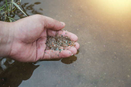 A close-up, side-view photograph of microplastic residue on a person's hand. Concepts related to water pollution and global warming. Concepts related to climate change.