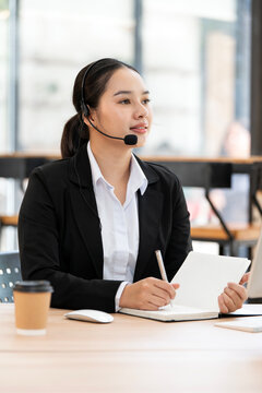 Asian Support Agent with Headset and Notebook in Modern Office
