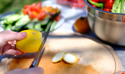 Freshness. A woman with a belly confidently cuts a fresh lemon in a housewife's home kitchen. Concept housewife woman hands cutting lemon applies cutlery, ingredient © Oleksandra
