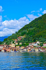 Fototapeta premium Blick vom Wasser auf das malerische Fischerdorf Peschiera Maraglio an den Hängen der Monte Isola im Iseosee, Italien