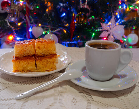 Greek orange pie and coffee on a handmade knitted tablecloth on the background of a Christmas tree in Greece