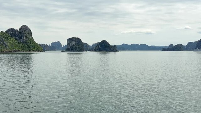 Panoramic view of limestone karsts and islands in Halong bay, Vietnam with calm water under overcast sky, perfect for travel tourism and nature backgrounds