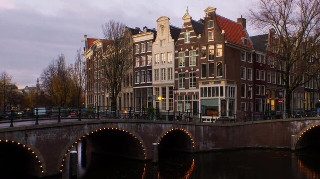 Amsterdam, Netherlands. Night view of canals and bridges in Amsterdam, Netherlands. Time-lapse of Keizersgracht and famous touristic place at sunset with illuminated houses, panning video