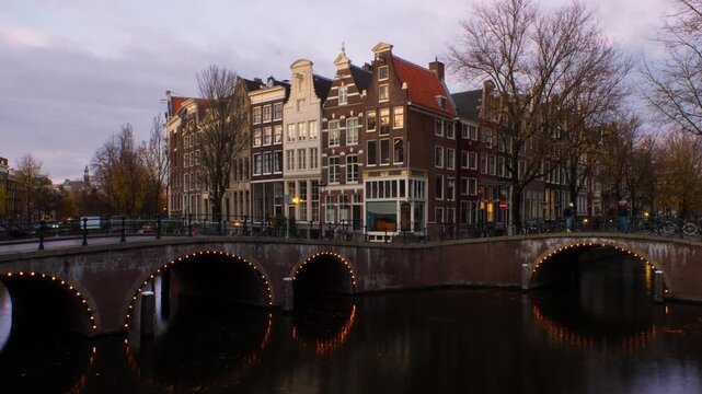 Amsterdam, Netherlands. Night view of canals and bridges in Amsterdam, Netherlands. Time-lapse of Keizersgracht and famous touristic place at sunset with illuminated houses, zoom in