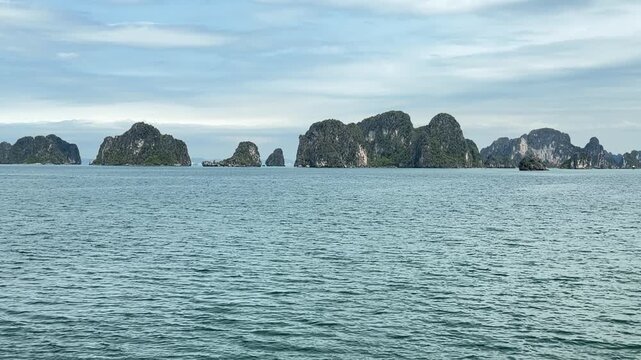 scenic limestone karst islands rising from calm waters in halong bay vietnam, peaceful tropical seascape, travel and tourism destination