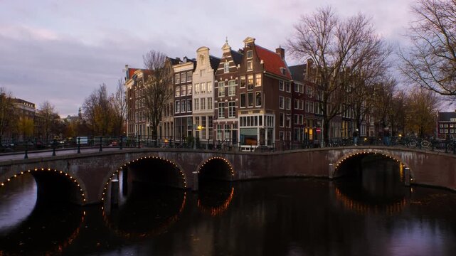 Amsterdam, Netherlands. Night view of canals and bridges in Amsterdam, Netherlands. Time-lapse of Keizersgracht and famous touristic place at sunset with illuminated houses