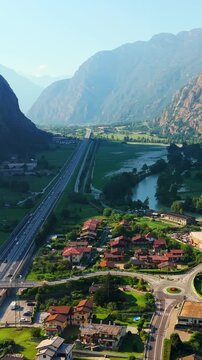 Vertical drone moving forward over alpine valley with road and Dora Baltea river in Aosta Valley Italy
