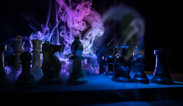 Chess board game concept of business ideas and competition. Chess figures on a dark background with smoke and fog.