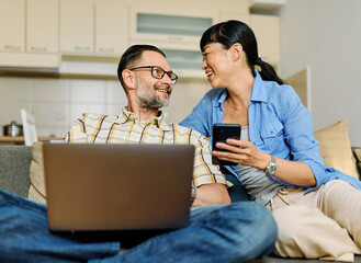 Portrait of a lovely young couple using a laptop and a mobile phone  together and having fun...