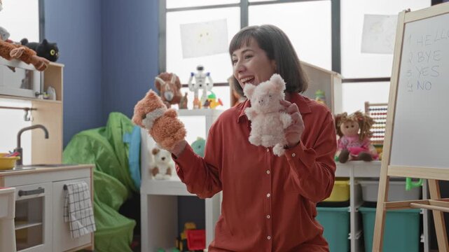 Woman teacher holds plush pig puppet and fox hand puppet, smiles and gestures with puppets in building; playful learning joy.
