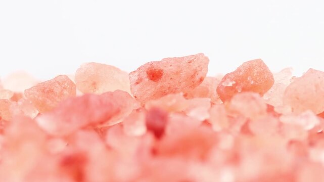 Close-up of pink himalayan salt rotating slowly on a white background