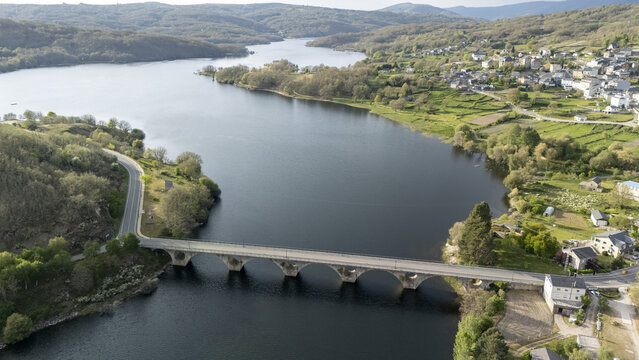 Aerial view of Encoro de Prada reservoir with a stone arch bridge crossing the water near the village of A Veiga, Ourense, Spain.