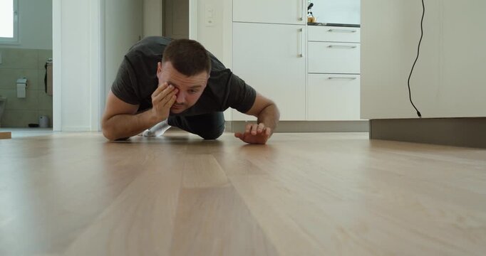 Man kneeling on the floor searching for a lost contact lens, representing vision problems and everyday challenges.
