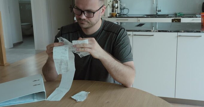 Man sitting at table overwhelmed by receipts, representing financial stress, budgeting problems, and money management issues.