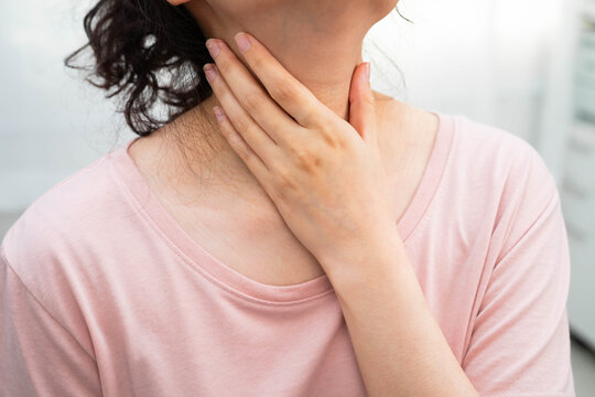Asian woman touching her neck and throat for thyroid gland problem.