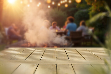 Naklejka premium Empty wooden table with clean copy space for product placement in the foreground. Blurred background with garden camping scene with barbecue grill and people enjoying outdoor time, warm, relaxed.