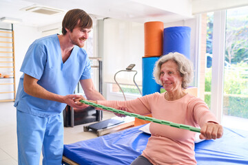 Obraz premium Senior Woman Doing Arm Exercises With Assistance From Physiotherapist In Rehab Center For Recovery And Improved Mobility Indoors