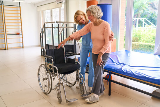 Physiotherapist Assisting Senior Woman With Wheelchair In Rehab Center For Mobility And Recovery After Injury Or Surgery Indoors