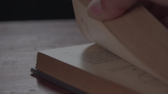 A close-up of a man&rsquo;s hand flipping through a book in slow motion. Hand Flipping Pages In A Book