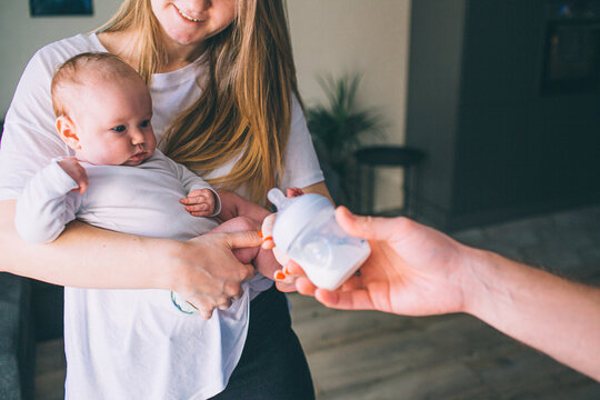 Portrait of a newborn baby. Mother holds a child in her arms. The first year of life. Care and health. ather gives a child a father gives the baby a bottle of breast milk.