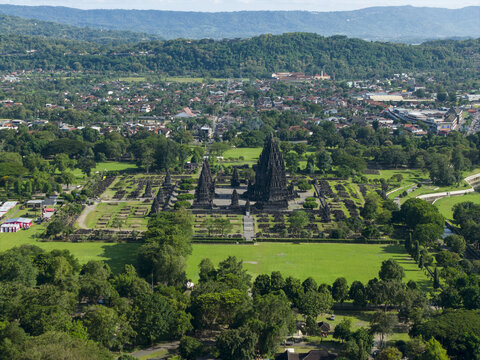 Aerial view of the ancient Prambanan Temple complex with its towering stone spires surrounded by lush green lawns and trees in Prambanan, Daerah Istimewa Yogya, Indonesia.
