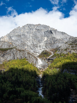 Rocky mountain with waterfall in Jiuzhaigou Valley Sichuan China, dramatic cliff landscape with forest and cascading stream, scenic alpine nature in UNESCO world heritage travel destination