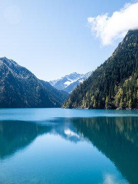 Jiuzhaigou Valley national park in Sichuan China with turquoise lake and mountain reflection, crystal clear water surrounded by forest and snow peaks, scenic UNESCO world heritage travel landscape