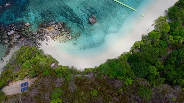 Aerial top view of a tropical paradise beach island with green forest eco system and crystal clear turquoise water and white sand beach background