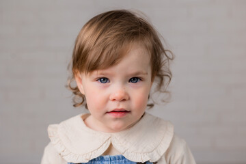 Naklejka premium portrait of a little girl with blond curly hair and blue eyes