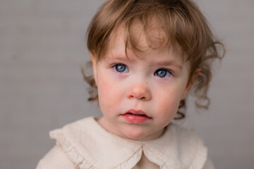 Naklejka premium portrait of a little girl with blond curly hair and blue eyes