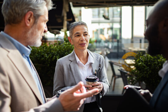 Senior business professionals networking with coffee at outdoor cafe