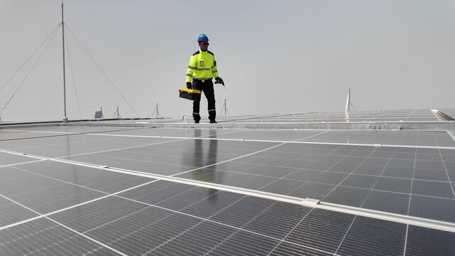 Solar panel technician working on rooftop installation with tools and safety gear