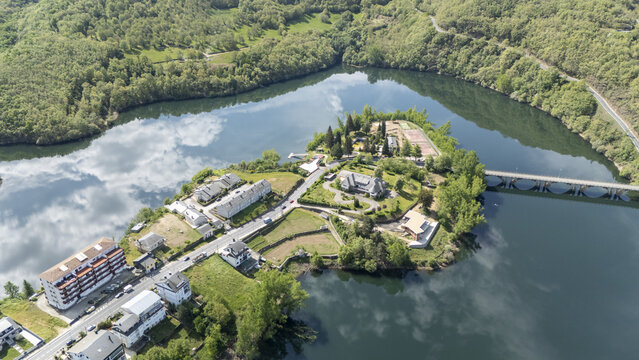 Aerial view of the town on a peninsula surrounded by calm waters reflecting white clouds and lush green hills Viana do Bolo, Province of Ourense, Spain.