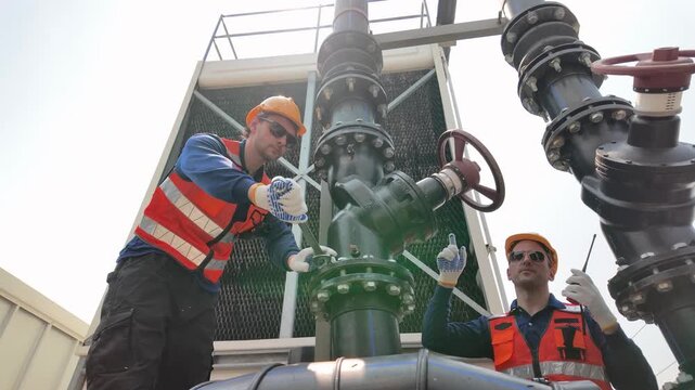 Industrial worker operating large valve on pipe system outdoors