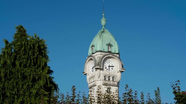 Clock tower with its green dome of the B&eacute;n&eacute;dictins railway station in Limoges under an azure sky in a fixed shot.