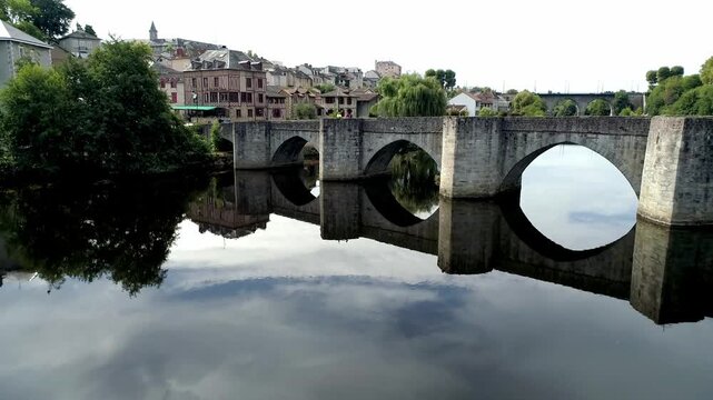 Medieval stone bridge architecture spanning the Vienne river in the town of Limoges. Arches and river water movement captured in a drone flyover.