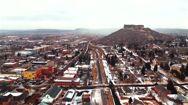 Castle Rock Colorado aerial drone Front Range south Denver city snow covered mesa snowy winter morning snowing cloudy day cars railroad track building neighborhood downtown backwards pan motion