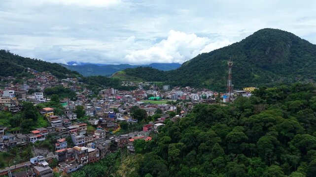 Rio de Janeiro. Colorful houses over hillside neighborhood at Praia do Anil, Angra dos Reis, surrounded by lush tropical vegetation and cloudy skies. Smooth left tracking aerial.