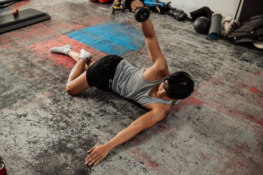 Young Asian man does side lying lateral raise at the gym focusing on shoulder isolation and controlled resistance training for muscle development