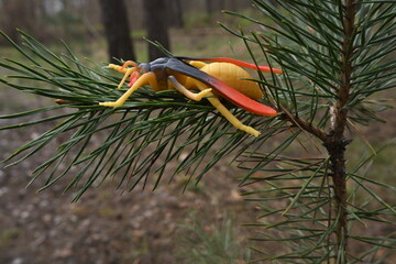 Obraz premium Toy insect sitting on a green pine branch capturing childhood and outdoor exploration wonder