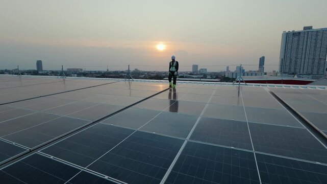 Rooftop solar panel installation worker inspects array at sunset with city skyline