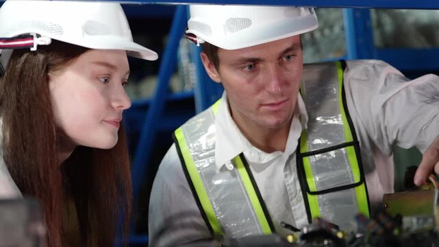 Two engineers collaborating on a complex electronic device in a workshop setting