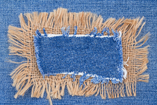 Patch for denim fabric showing frayed edges and blue color with tan background used for repair in sewing projects