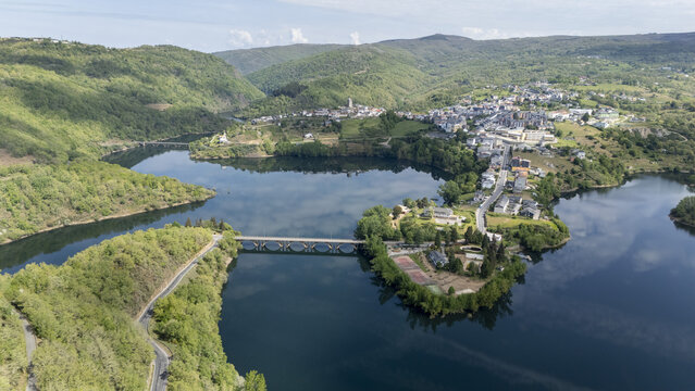 Aerial view of the town of Viana do Bolo surrounded by the calm waters of the Bao Reservoir and lush green hills under a bright sky Viana do Bolo, Province of Ourense, Spain.