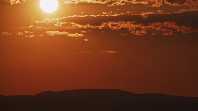 Dramatic Sunset Timelapse with Sun and Clouds Over Mountain Silhouette Zoom Out