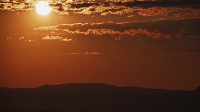 Dramatic Sunset Timelapse with Sun and Clouds Over Mountain Silhouette