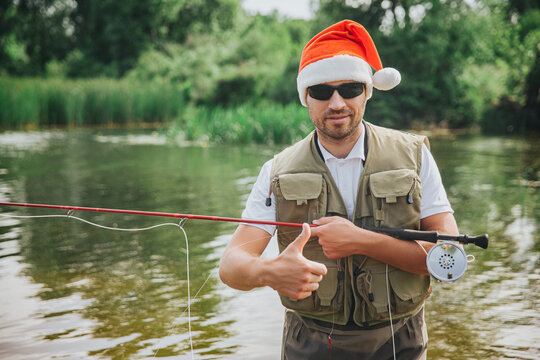 Young fisherman fishing on lake or river. New year period or Christmas time. Guy holding rod for fishing. Festive time during holidays. 2021 celebrating.