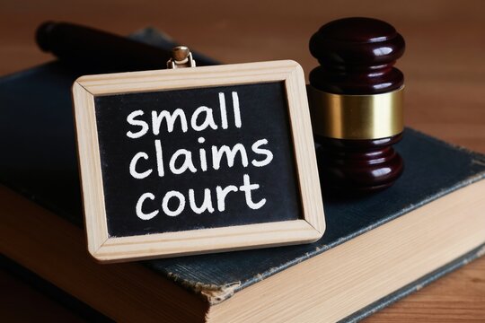 Small claims court sign on book next to gavel. Legal dispute resolution concept. Justice, law and order symbol. Civil litigation process and legal proceedings.