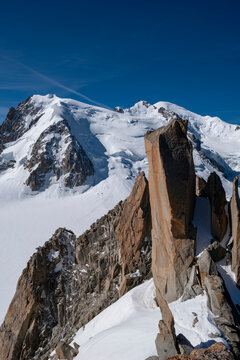 Ar&ecirc;te des Cosmiques and Towering granite pinnacles with snow-covered slopes overlooking the Mont Blanc massif, a dramatic high-altitude mountaineering route under clear blue sky , Chamonix, France.