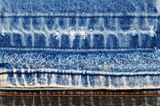 Different layers of denim fabric stacked together showing texture and design in a close-up view during daylight